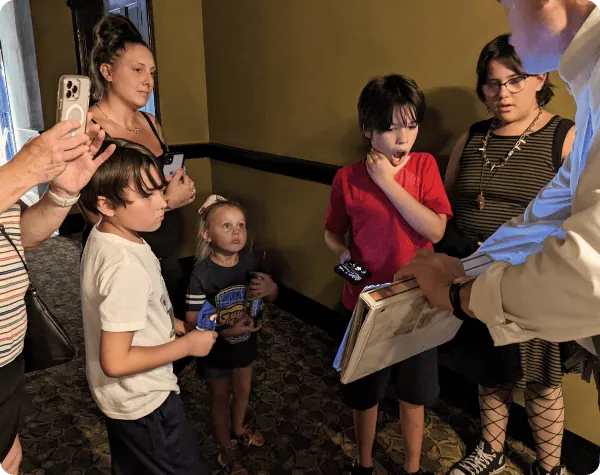 Ghost tour guide showing haunted artifact to children on a kid's ghost tour